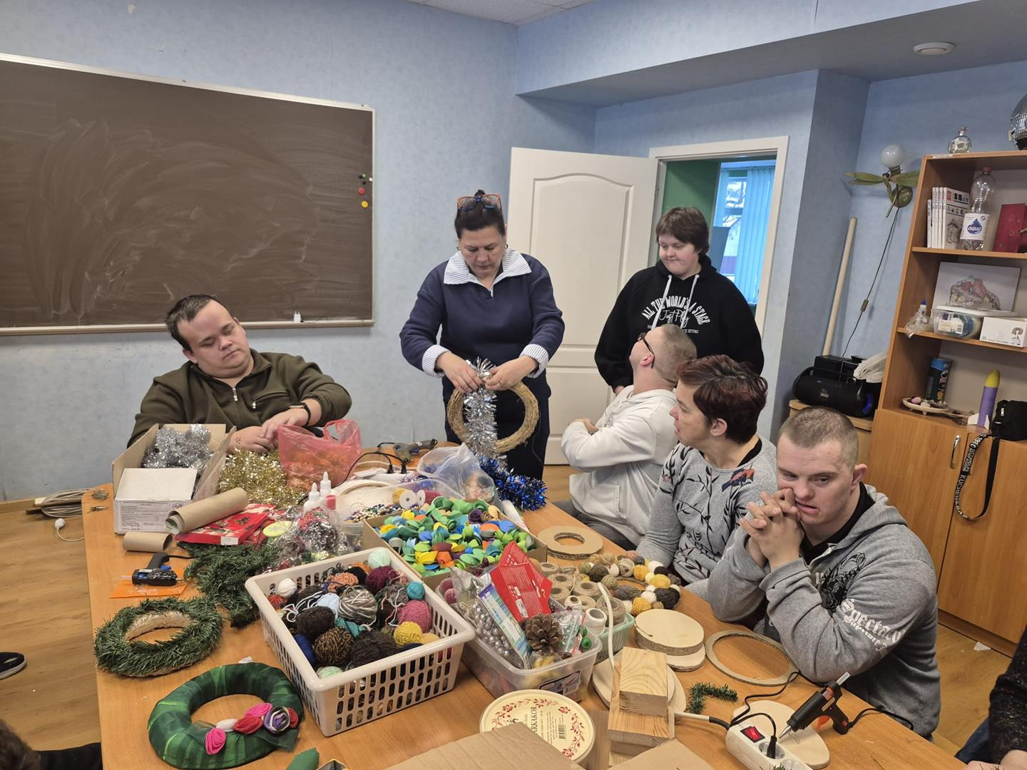 Cilvēki pie galda gatavo ziemassvētku rotājumus