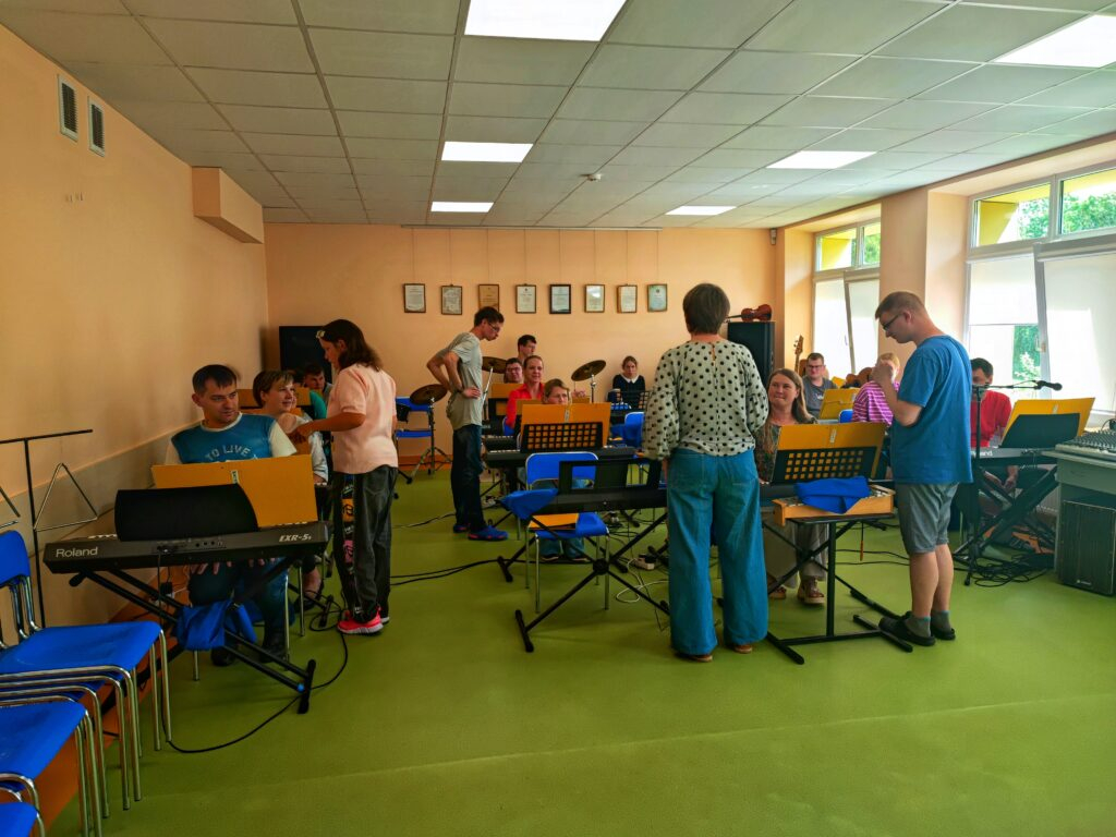 Cilvēki telpā pie mūzikas instrumentiem