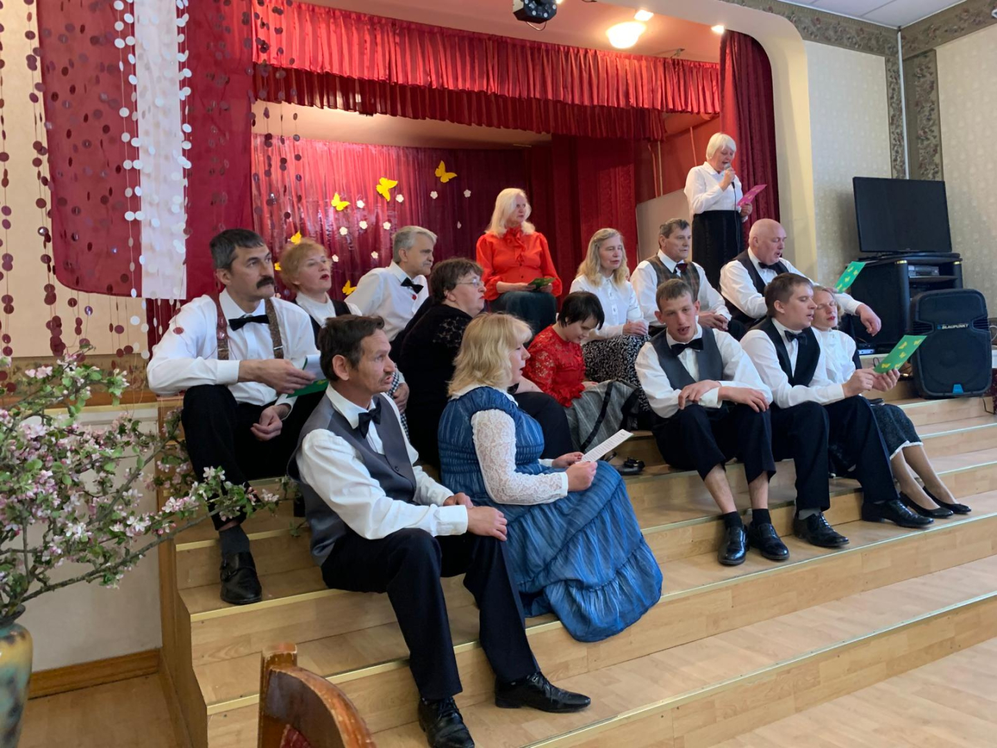 Cilvēku grupa sēž uz skatuves kāpnēm