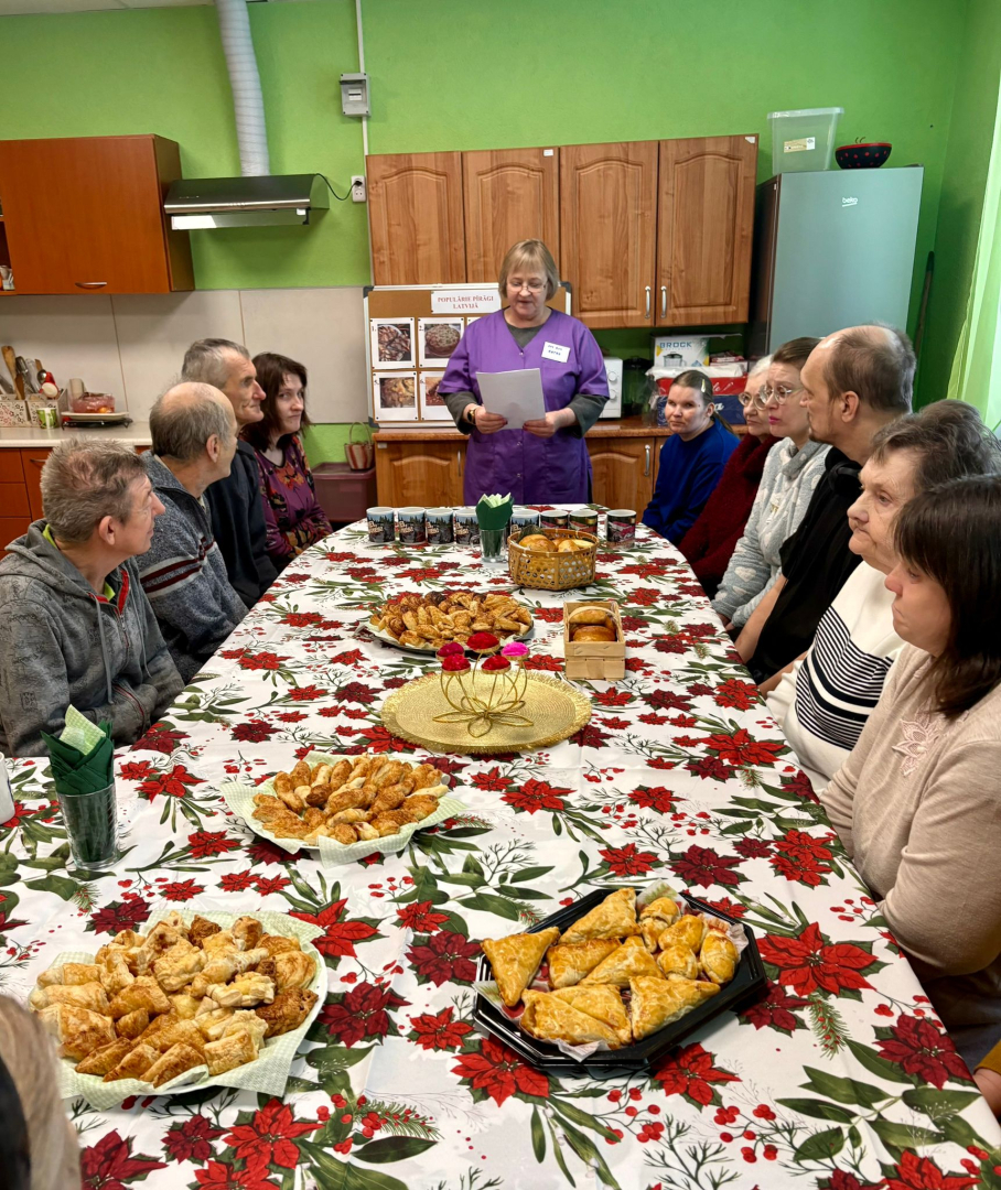 Cilvēki pie galda, uz galda pīrāgi