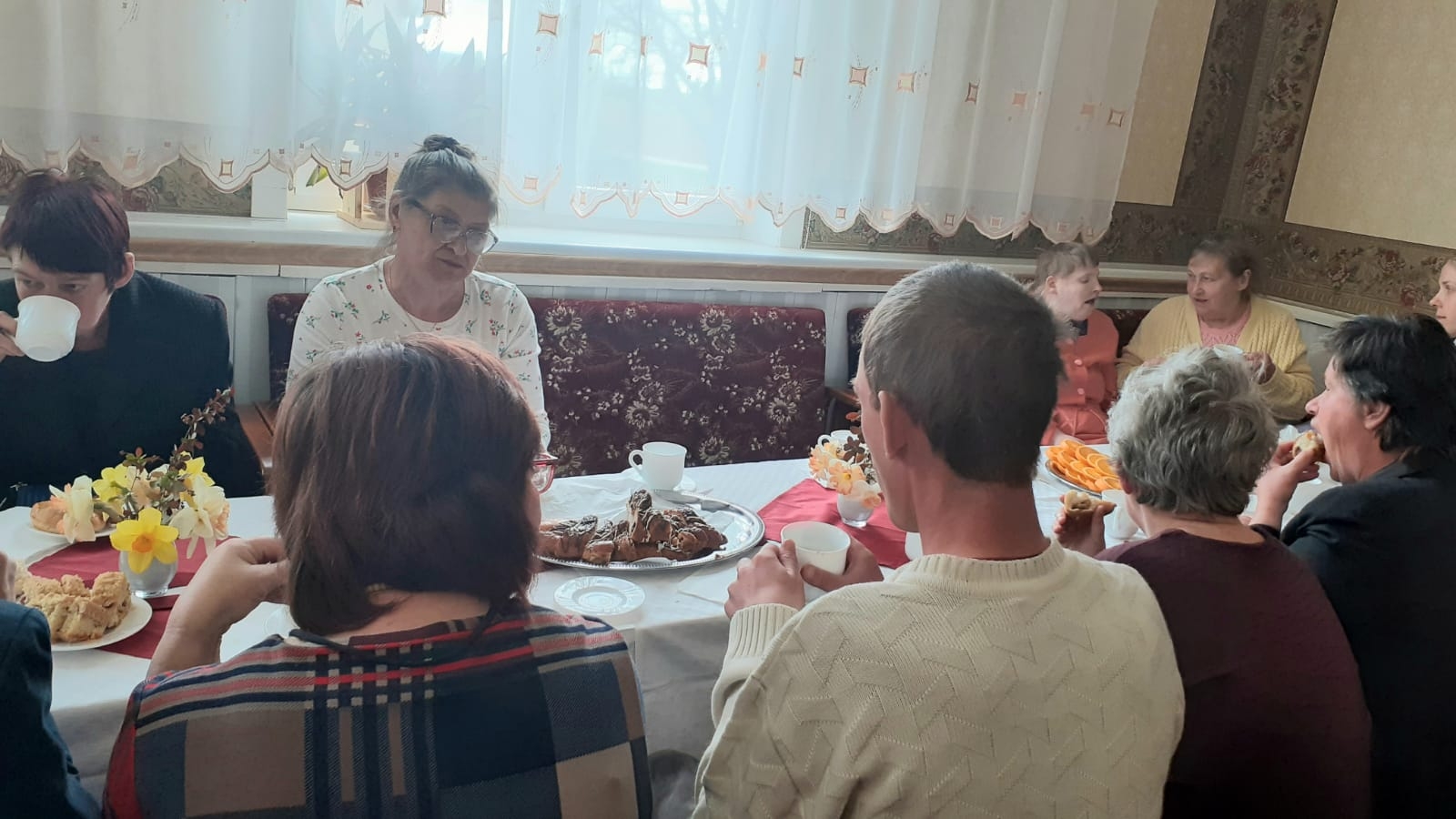 Cilvēki sēž pie svētku galda ar  ēdieniem