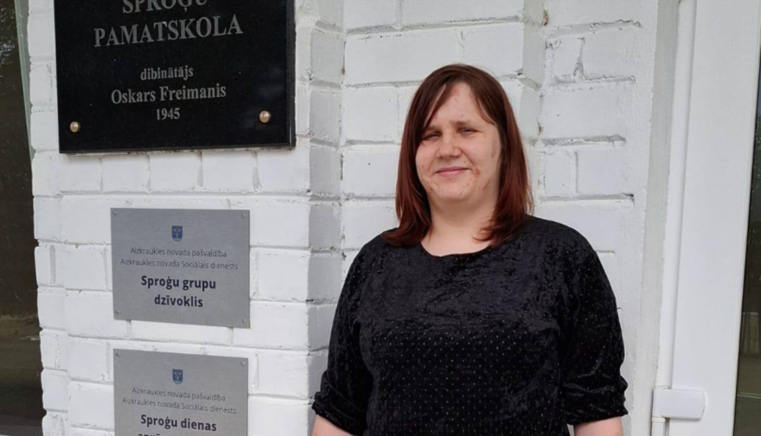 Sieviete stāv pie ēkas ieejas