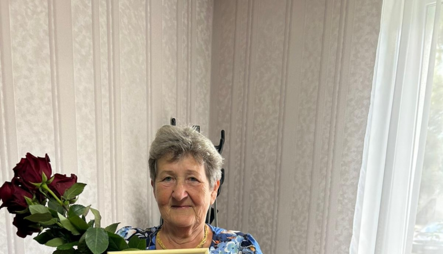 Sieviete tura rokā godarakstu un ziedus